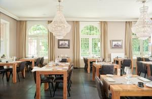 a restaurant with wooden tables and chairs and windows at De Statie in Brecht