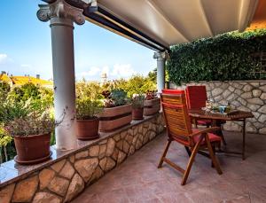 a patio with a table and chairs and potted plants at Villa Magnolija in Cres