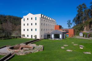 a large white building with a green field in front of it at HD | Duecitânia Design Hotel in Penela