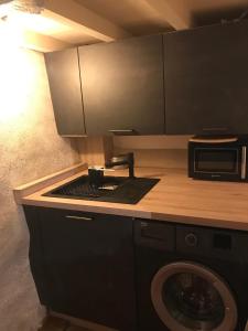 a kitchen with a washing machine and a microwave at LA MAISON DU BOSCO in Auray