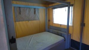 a small bed in a room with a window at La tente de la plage in Plouha