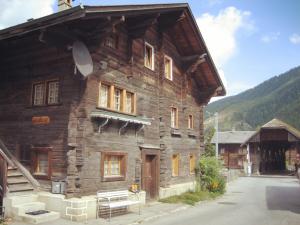 a large wooden building with windows on a street at Bi de Furre in Reckingen - Gluringen