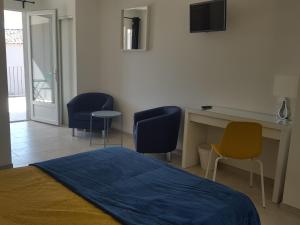 a bedroom with a bed and chairs and a desk at Résidence Les Pavillons du Belvédère in Porto-Vecchio