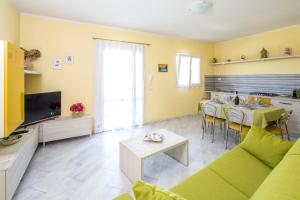 a living room with a green couch and a kitchen at Borgo dell'Uccellaia - Turchese - Giada in Marciana Marina