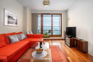 un salon avec un canapé rouge et une télévision dans l'établissement Sea Towers "Sweet Dream", à Gdynia