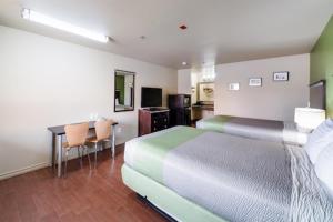 a bedroom with a bed and a desk and a kitchen at Eagle Ford Inn in Floresville