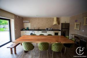 a kitchen with a wooden table and green chairs at Casas do Picoutinho in Ponte de Lima