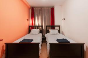 2 łóżka w małym pokoju z czerwonymi zasłonami w obiekcie Negroni Apartments w Krakowie
