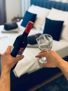 una persona sosteniendo una botella de vino y una copa en Apart Rooms Sova en Novi Sad