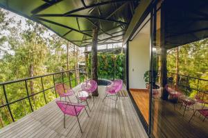 a room with pink chairs and a table on a balcony at Hotel Mumu Guatapé in Guatapé