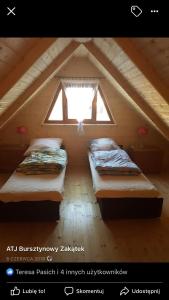 two beds in a attic room with a window at ATJ Bursztynowy Zakątek in Kąty Rybackie