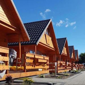 uma fila de edifícios de madeira com painéis solares em ATJ Bursztynowy Zakątek em Kąty Rybackie