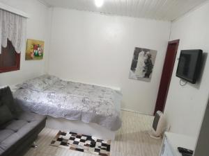 a bedroom with a bed and a couch and a tv at Hospedagem dona Tania in Canela