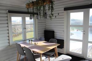 uma sala de jantar com mesa, cadeiras e janelas em Hyggely - A Place By The Sea - Nørre Lyngby em Lokken
