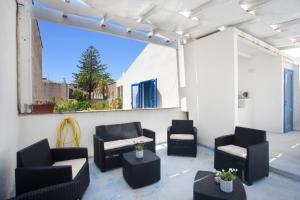 a patio with black chairs and tables and a white wall at Blusanvito in San Vito lo Capo