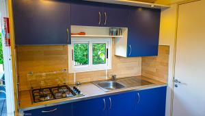 a kitchen with blue cabinets and a sink and a window at Urlaub am Wallersee in Seekirchen am Wallersee