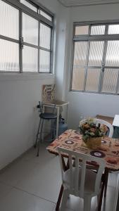 uma sala de jantar com mesa, cadeiras e janelas em Apto Sao Vicente em São Vicente
