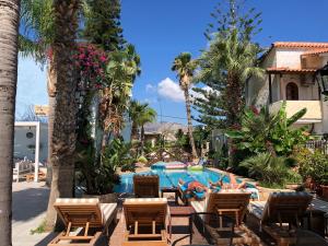 een resort met een zwembad, stoelen en palmbomen bij Minoa Apartments in Amoudara Herakliou