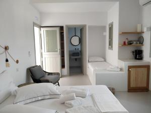 a white room with two beds and a chair at Psathaki in Kimolos