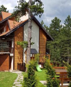 une maison avec un arbre en face dans l'établissement Apartmani Lotos, à Kaluđerske Bare