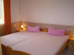 a white bed with pink pillows in a room at Ferienhaus nahe am Meer in Sant Lluis