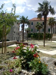 a park with flowers and a bench in front of a building at Old school apartment in Kaštela