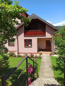 a pink house with a gate and flowers at Apartman Vukan in Bajina Bašta
