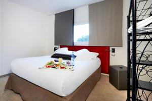 - un grand lit blanc avec un plateau de nourriture dans l'établissement Hôtel restaurant Kyriad Fréjus, à Fréjus