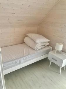 a small bed in a small room with a table at Domki Kalmar Sarbinowo in Sarbinowo