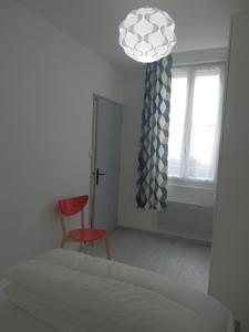 een slaapkamer met een bed, een rode stoel en een raam bij Appartement T2 ou T1 côté cour/jardin avec garage in Rochefort