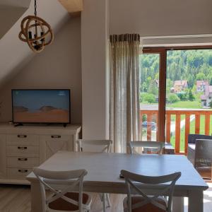 a dining room with a table and a large window at Apartamenty Homole Mansarda in Szczawnica
