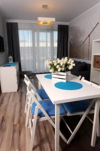 uma sala de jantar com uma mesa branca e cadeiras azuis em Apartament Ster Kołobrzeg em Kolobrzeg