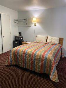 ein Hotelzimmer mit einem Bett mit einer bunten Decke in der Unterkunft Regency Inn Comanche in Comanche