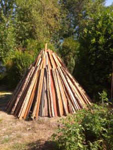 una pila de vigas de madera sentadas en el césped en Chambres d'Hôtes La Turone, en Cheillé