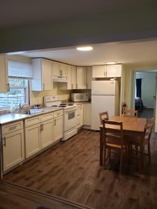 cocina con armarios blancos, mesa, mesa y sillas en Homeward Inns of Canada en Antigonish