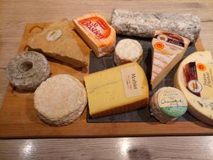 a wooden tray with different types of cheese and bread at Chambres d'Hôtes La Turone in Cheillé