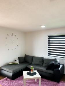 a living room with a couch and a clock on the wall at Modern Apartment in Brčko