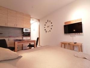 a bedroom with a bed and a desk and a clock on the wall at Studio 20qm mit Balkon und Innenpool - 22040 in Schluchsee
