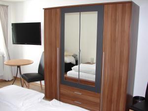 a wooden cabinet with a mirror in a bedroom at Gasthaus zur Traube in Winterrieden