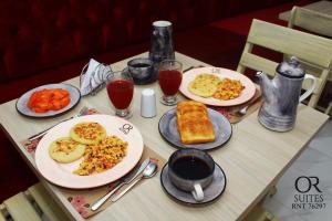 a table with plates of breakfast food and drinks at Hotel OR Suites in Barranquilla