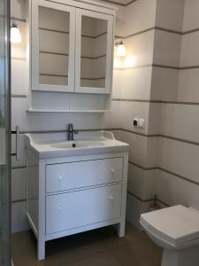 La salle de bains est pourvue d'un lavabo blanc et de toilettes. dans l'établissement Apartament Bliżej Morza, à Kołobrzeg