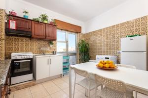 a kitchen with white appliances and a table with a bowl of fruit at Sea View Fairy Tale in Faro
