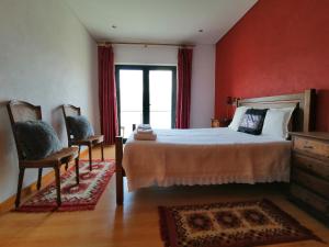 sypialnia z łóżkiem z czerwonymi ścianami i 2 krzesłami w obiekcie Gerês e Cabreira - Casa Alexandrina Vilar w mieście Frades