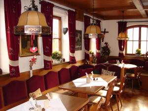 a restaurant with tables and chairs and red curtains at Gasthaus zur Traube in Winterrieden