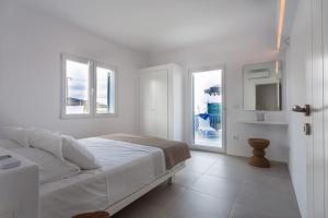 a white bedroom with a bed and two windows at Flag Suites in Pollonia