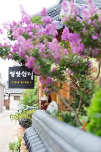 a bunch of pink flowers hanging from a building at Starlight Rest Area in Jeonju