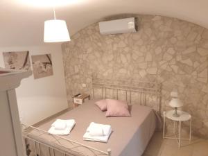 1 dormitorio con cama y pared de piedra en AP Apartment - Spiaggia della Purità, en Gallipoli