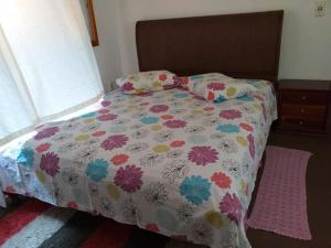 a bedroom with a bed with a flowered comforter and a window at Cantinho da Serra in Santo Antônio do Pinhal