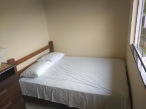 a bedroom with a bed with white sheets and a window at Casa com vista para o Mar in Ilhabela