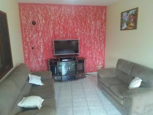 a living room with two couches and a flat screen tv at Casa com vista para o Mar in Ilhabela